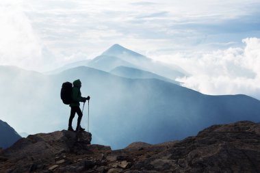 Sisli Karpat dağlarının nefes kesici arka planına karşı sırt çantalı siluet. Seyahat ve macera konsepti