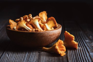 Koyu renkli mantarlı ahşap bir kase. Orman yemekleri, sonbahar mevsimi, doğal malzemeler.