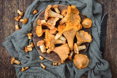 Chanterelle mantarları ahşap yüzeye saçılmış keten kumaşlar. Yaban mantarları, organik malzemeler, kırsal yaşam.