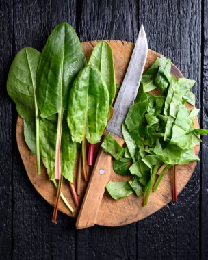 Yuvarlak kesme tahtasının üzerinde eski model bir bıçak ve düz bir iple genç bir kuş sürüsü. Genel yemek fotoğrafçılığı, doğal yeşiller, kırsal mutfak sahneleri.