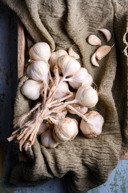 Ahşap kutu sarımsak ampulleriyle dolu, dokulu mutfak bezine karanfil konmuş. Kırsal besin bileşiminde çiğ organik sebzeler. Düz yatış, üst görünüm