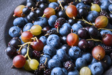 Çeşitli mavi ve yeşil böğürtlenler yakın perspektif, sığ alan derinliği. Yaban mersini, dut ve bektaşi üzümü, sağlıklı mevsimlik meyve.