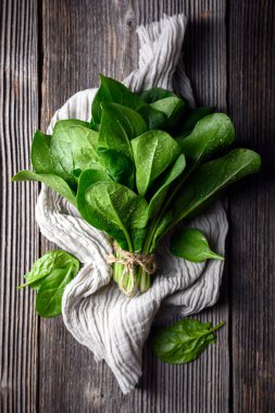 Pamuklu mutfak bezine sarılı ıspanak yığını. Ev bahçıvanlığı, temiz sebzeler ve eko yaşam tarzı konsepti