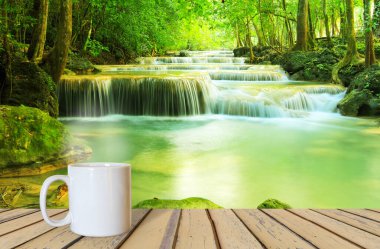 Şelaleye karşı ahşap bir masada bir fincan kahve.