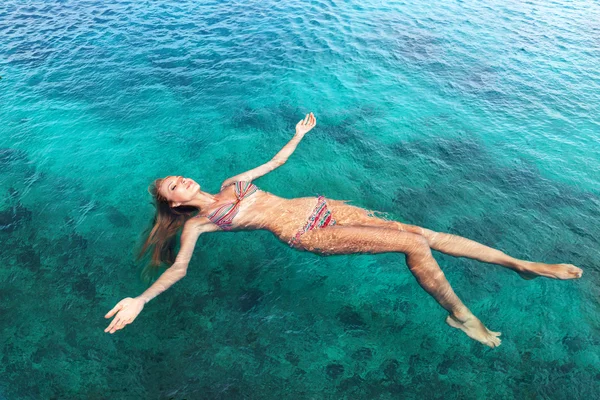 Mulher de biquíni relaxante deitada na água — Fotografia de Stock