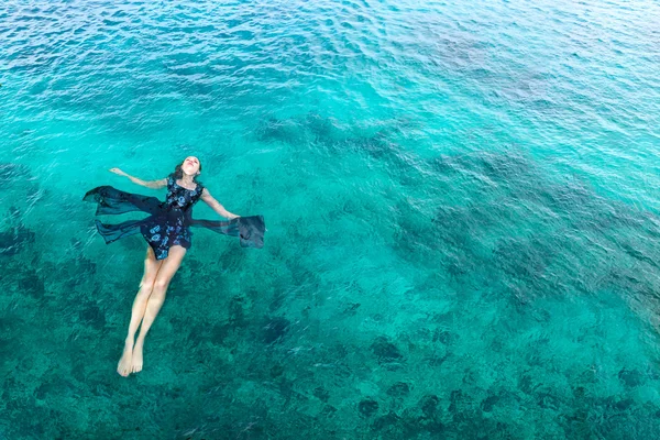 Mujer en vestido relajante acostada en el agua — Foto de Stock