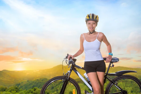 Młoda kobieta z rowerem na górskiej drodze — Zdjęcie stockowe