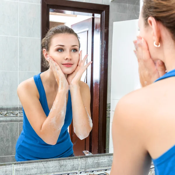 Jonge vrouw haar gezicht wassen — Stockfoto