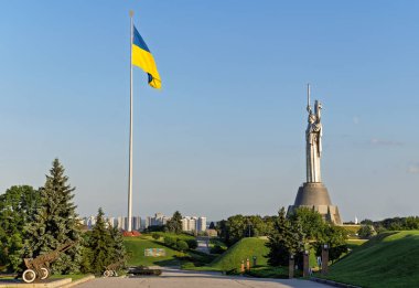 Ukrayna bayrağı havada dalgalanıyor. Kyiv. Rusya 'nın Ukrayna' ya karşı savaşı. Anavatanın ünlü heykelinin manzarası. Bağımsızlık. Özgür bir ülkenin kırılmaz başkenti..