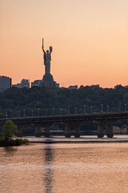 Gün batımı manzarası. İkonik Kyiv şehir manzarası. Rusya 'nın Ukrayna' ya karşı savaşı. Dnipro Nehri 'nin sağ kıyısındaki ünlü Anavatan Anıtı' nın manzarası. Bağımsızlık. Özgür bir ülkenin kırılmaz başkenti..