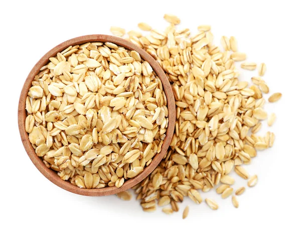 Raw oatmeal in a wooden plate on a white background, isolated. The view from top Stock Picture