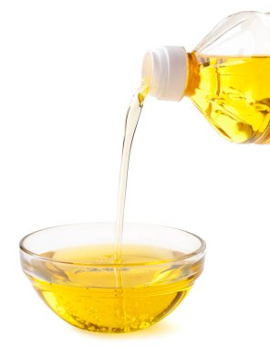 Bir şişeden çıkan ayçiçeği yağı beyaz arka plandaki cam bir kaseye dökülür. İzole edilmiş