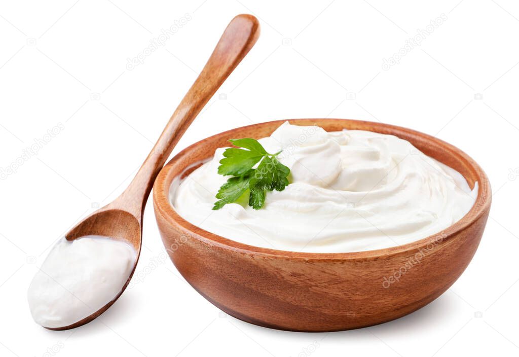 Sour cream in a wooden plate and spoon close-up on a white background. Isolated