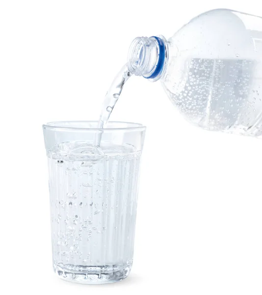 白い背景のガラスのクローズアップにボトルから水が注いでいます — ストック写真