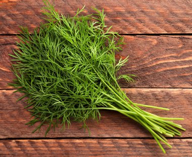 Ahşap bir arka planda bir sürü taze dereotu yakın plan. Üst görünüm