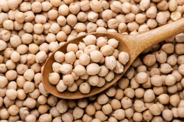 Chickpeas in a wooden spoon close up, background. Top view