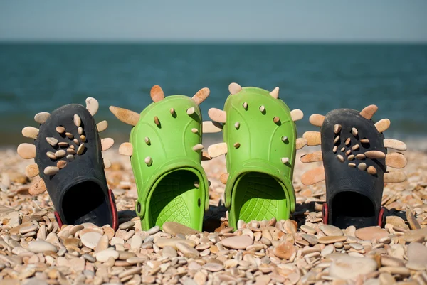 Crocs met stenen op het strand — Stockfoto