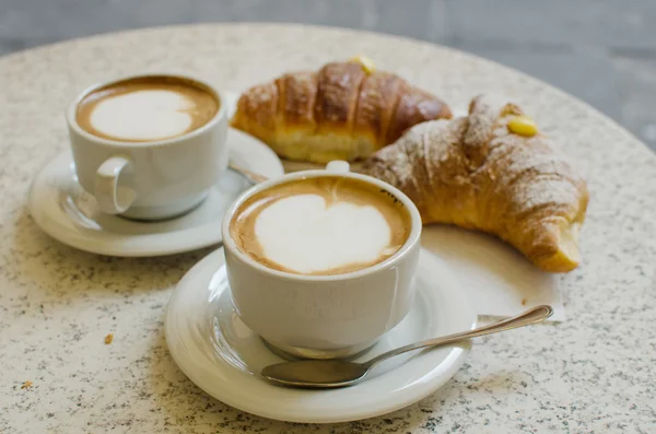 Two cups of cappuccino with two croissants. — Stock Photo, Image