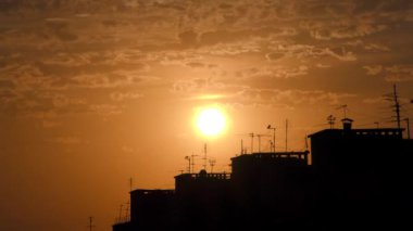 Arka planda şehirle birlikte bulutlu günbatımının zaman akışı