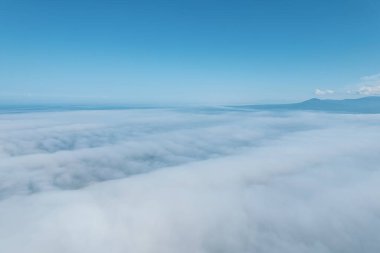 Dağların tepesinde bulutlar arasında uçuyor. Yüksek tepeler, harika sabah güneşi, doğal manzara.