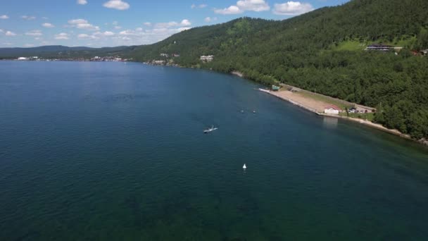 Jezioro Bajkał to wspaniały niebieski klejnot otoczony malowniczymi górami i lasami. Epicki widok z lotu ptaka na jezioro Baikal. Widok z lotu ptaka na jezioro i zielone lasy. — Wideo stockowe