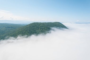 Dağların tepesinde bulutlar arasında uçuyor. Yüksek tepeler, harika sabah güneşi, doğal manzara.