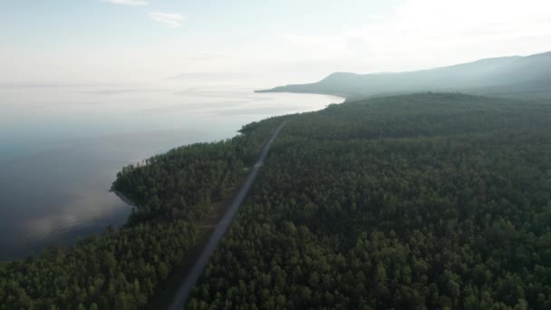 Epic vista aérea cinematográfica Lago Baikal por la mañana. Agua turquesa en un lago de bosque montañoso con pinos. Vista aérea del lago azul y bosques verdes. Vista sobre el lago entre el bosque de montaña. — Vídeo de stock