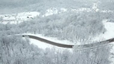 Drones Eye View - kışın yüksek dağ geçidinden dolambaçlı yol. Yoğun ormanda harika bir yolculuk..