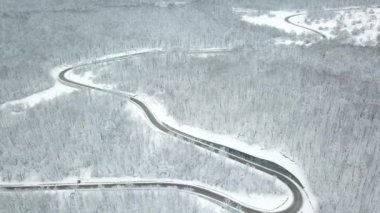 Drones Eye View - kışın yüksek dağ geçidinden dolambaçlı yol. Yoğun ormanda harika bir yolculuk..