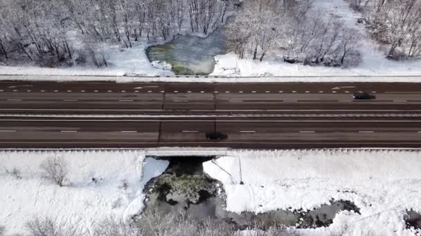 Vintertid antenn topp ner utsikt över en snöig väg omgiven tallskog — Stockvideo