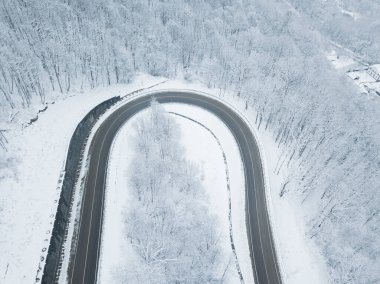 Drones Eye View - Güney Rusya 'daki yüksek dağ geçidinden gelen kış virajı yolu. Yoğun ormanda harika bir yolculuk..