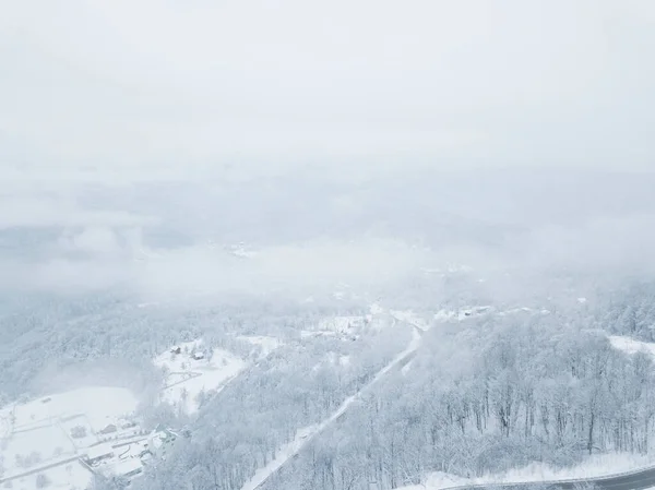 无人机眼景-冬季蜿蜒的公路从俄罗斯南部的高山山口。一路顺风穿过茂密的树林. — 图库照片