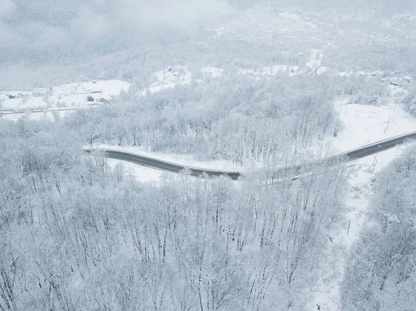 无人机眼景-冬季蜿蜒的公路从俄罗斯南部的高山山口。一路顺风穿过茂密的树林. — 图库照片