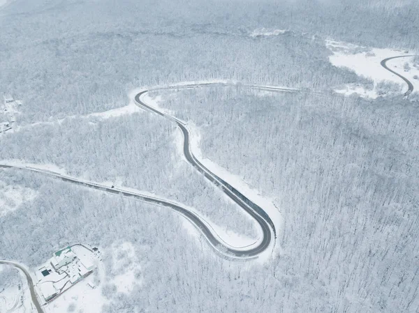 无人机眼景-冬季蜿蜒的公路从俄罗斯南部的高山山口。一路顺风穿过茂密的树林. — 图库照片