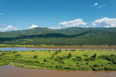 Sibirya 'daki bir buzul nehrinin üzerinde uçarken, arkasında yeşil dağlar ve tren yolu vardı..
