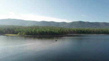 Baykal Gölü 'nün destansı sinematik manzarası. Bir dağ ormanı gölünde çam ağaçlarıyla birlikte turkuaz su. Mavi göl ve yeşil ormanların havadan görünüşü. Dağ ormanları arasındaki göle bak..