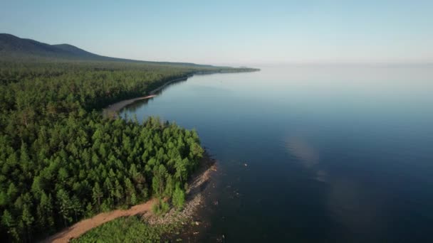 Epikus légi felvétel a Bajkál-tóról reggel. Türkiz víz a hegyi erdő tavában fenyőfákkal. Légi kilátás a kék tóra és a zöld erdőkre. Kilátás a tóra a hegyi erdők között. — Stock videók