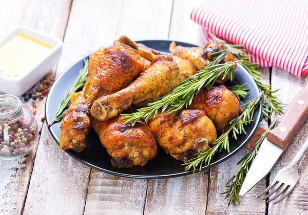 Baked chicken legs on black plate — Stock Photo, Image