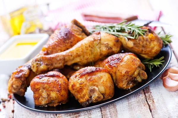 Baked chicken legs on black plate — Stock Photo, Image