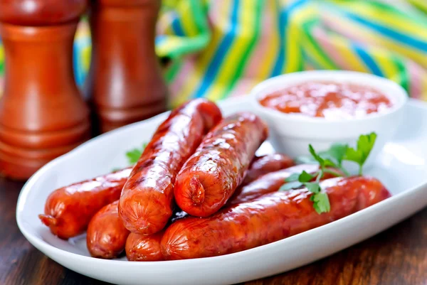 Sabrosas salchichas en plato con salsa —  Fotos de Stock