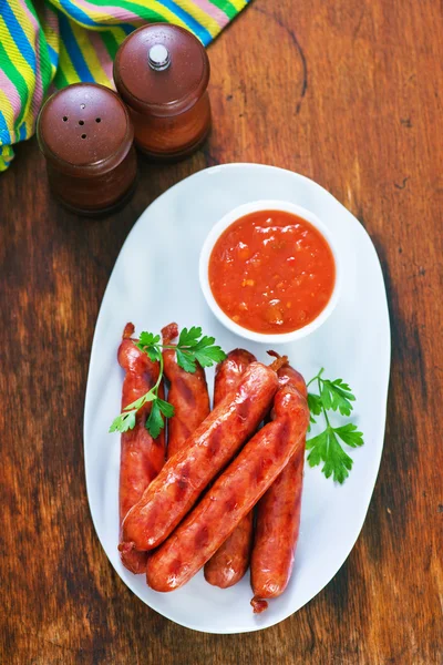 Sabrosas salchichas en plato con salsa —  Fotos de Stock