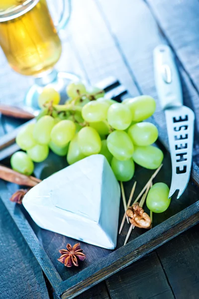 Formaggio con uva su un'asse — Foto Stock