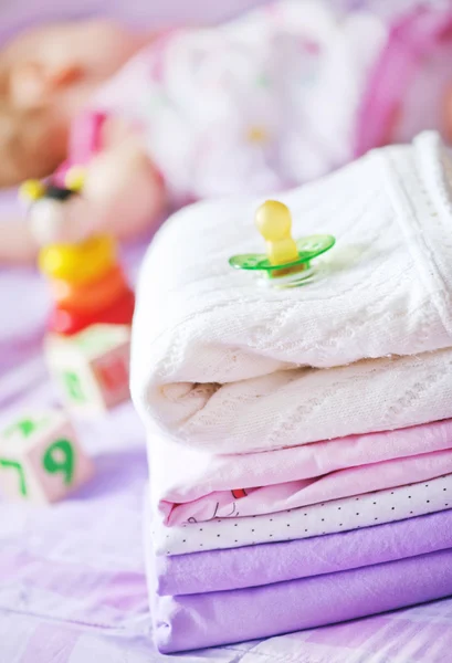 Roupas de bebê na cama — Fotografia de Stock