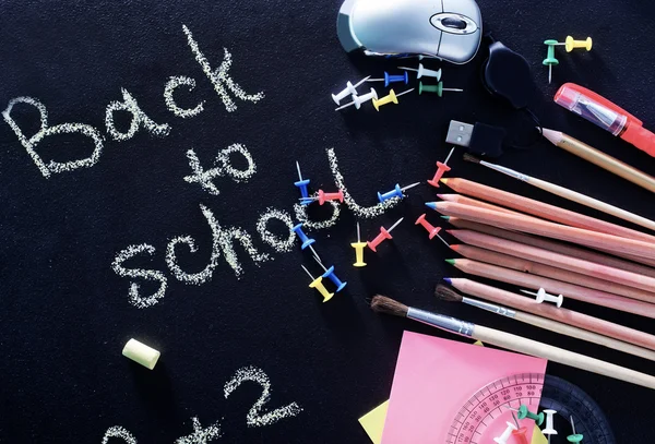 School supplies on blackboard — Stock Photo, Image