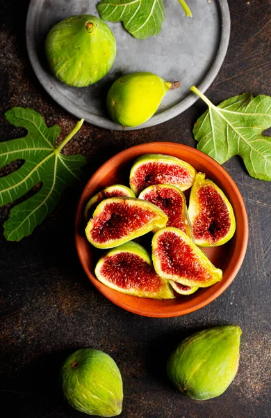 Ripe fig fruits with fig leaves on the brown background