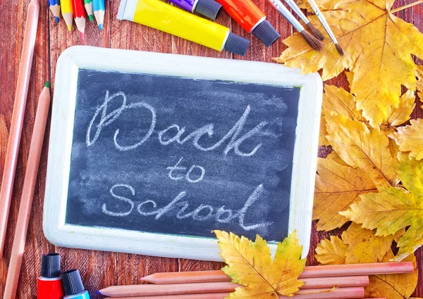Kreidetafel, Schulmaterial und Herbstblätter — Stockfoto