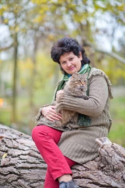 Senior woman with cat in autumn park — Stock Photo, Image