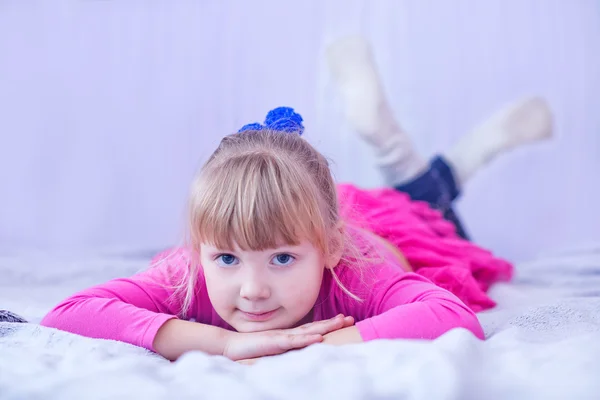 Улыбающаяся маленькая девочка лежит на кровати — стоковое фото