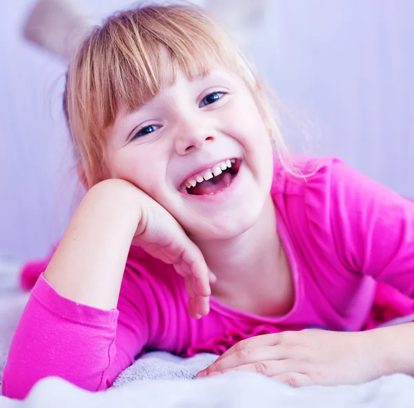 Lachende meisje liggend op bed — Stockfoto