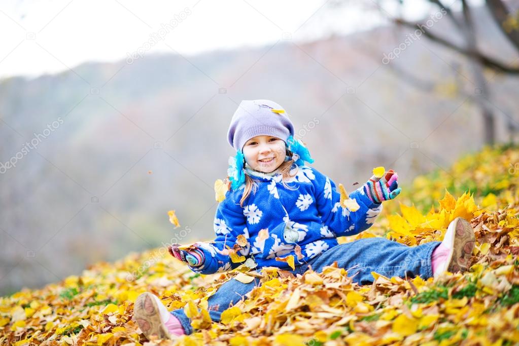 Girl playing with autumn leaves in park